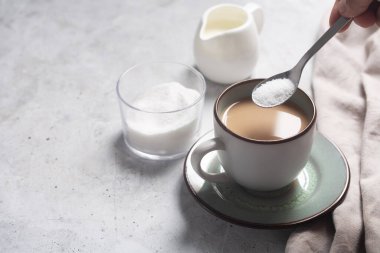 Sütlü kahve ve peçeteyle tatlandırıcılı kaşık. Boşluğu kopyala