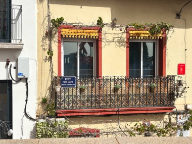 Alicante, İspanya - 15 Ekim 2025: Canlı bir balkon çiçekler ve kiralık bir tabela ile süslenmiş, güneşli bir şehir zeminine karşı dekoratif korkuluklar ve yeşillikle kurulmuş