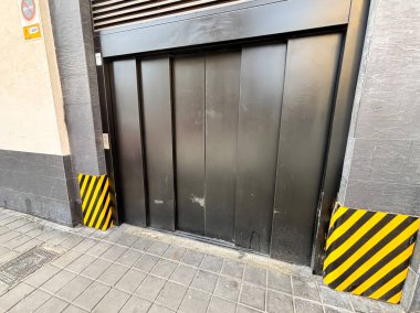 Alicante, İspanya - 15 Ekim 2025: Siyah garaj kapısında sarı ve siyah çizgili güvenlik işaretleri yer almaktadır.