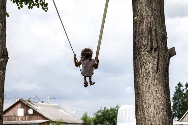 Girl riding a swing high among the trees