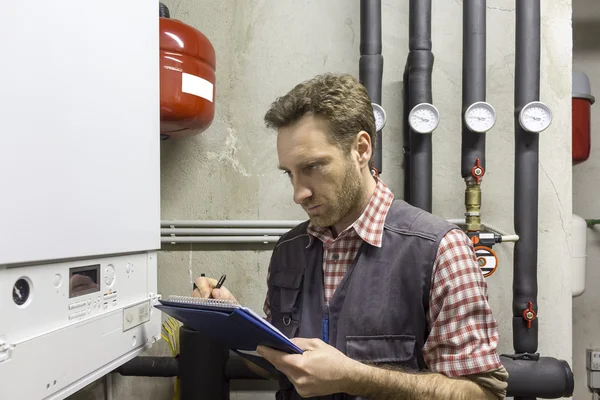 Plumber who carries out the maintenance of a condensing boiler — Stock Photo, Image