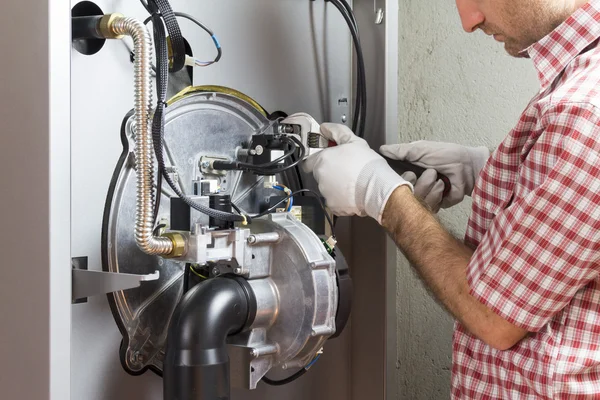 Fontanero reparación de una caldera de condensación en la sala de calderas — Foto de Stock