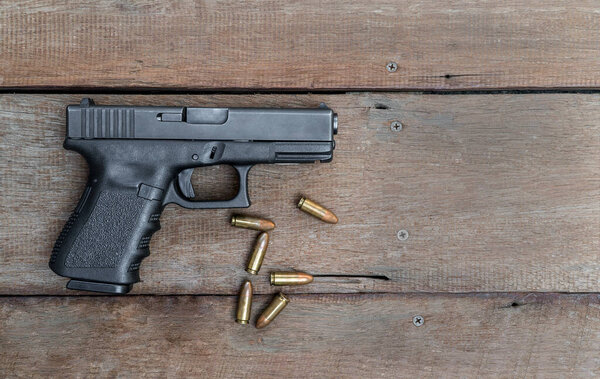 Black steel polymer semi-automatic 9mm pistol on wooden background with Copy Space