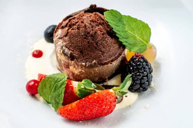 Çikolatalı tatlı krema ve nane yapraklarıyla süslenmiş taze böğürtlenlerle servis edilir. Doğal ışıklandırma ve temiz kaplama ile yüksek detaylı yiyecek fotoğrafçılığı