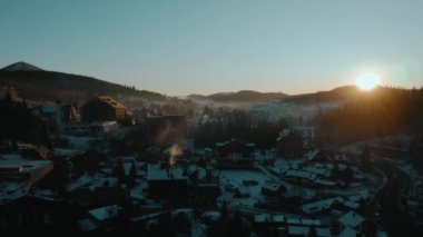 Kışın güneş doğarken dağlardaki bir köyün manzaralı manzarası.