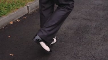 Asfalt kaplama üzerinde adım deri ayakkabıları parlayan siyah erkek ayakları