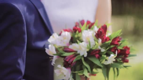 Bouquet de mariée rouge et blanc entre les mains de jeunes mariés — Video