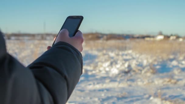 Manos de hombre usando el teléfono inteligente en invierno en la puesta del sol — Vídeo de stock