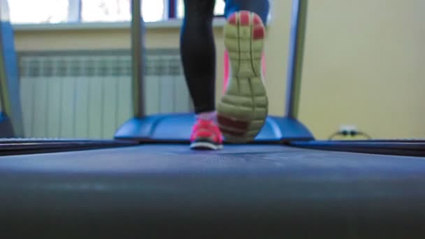 Närbild av kvinnans ben i rosa sneakers på ett löpband. Bakifrån. — Stockvideo