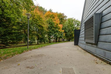 Captured in vertical format, this image shows a picturesque bridge scene by a calm river, where autumn trees and nearby buildings reflect in the wate  a serene composition full of balance and warmth.