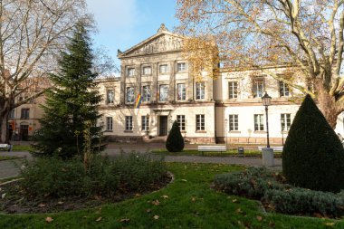 Tarihi Aula 'nın etkileyici solgunluğu, eski ağaçlar ve manikürlü yeşillikler tarafından çerçevelenmiş ve klasik mimari karakterini yansıtan ılık sonbahar ışığında belirir..