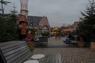 Wolfenbuettel 'deki Noel pazarında renkli çocuklar antrenman yapıyor. 25 Kasım 2025' te saat 15: 12 'de çekiliyor. Arka planda şenlikli dekorasyonlar ve yarım ahşap binalar görülüyor..