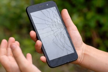 Bir çocuğun elinde kırılmış bir akıllı telefon. Akıllı telefon ekranı çöktü. Parçalar halinde akıllı telefon görüntüsü.