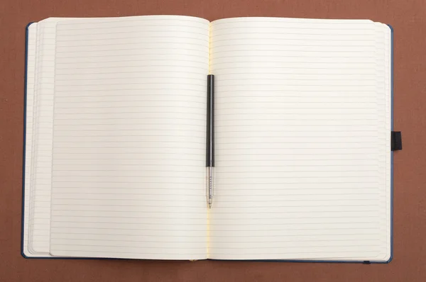 Blank notebook and black pen on brown background — Stock Photo, Image