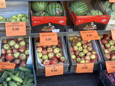 Varşova, Polonya - 24 Eylül 2025: Taze meyveler, renkli etiketli elmalar, karpuzlar ve salatalıklar sergilenen bir pazarda düzenlenir