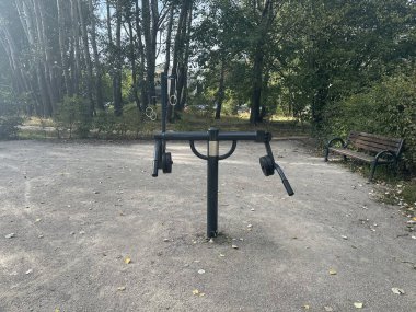 Varşova, Polonya - 24 Eylül 2025: Parktaki açık spor aletleri, yakınında ağaçlar ve bank olan çoklu egzersiz istasyonunu gösteriyor