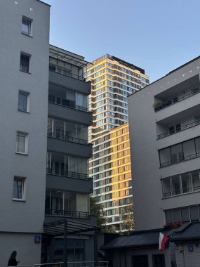 Varşova, Polonya - 24 Eylül 2025: Yüksek binalar güneş ışığında parlıyor, konut binaları arasına yerleşmiş, kentsel mimariyi ve modern yaşamı ön plana çıkarıyor