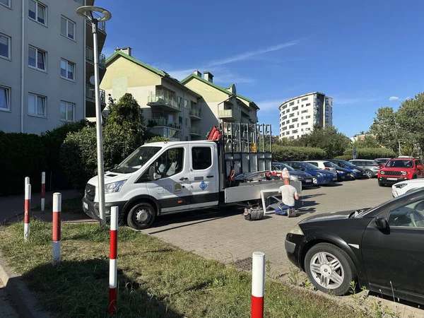 Varşova, Polonya - 24 Eylül 2025: Arabalar ve konut binalarıyla çevrili beyaz servis aracı teknisyenlerle birlikte sokağa park edildi