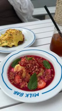 Varşova, Polonya - Eylül 2025: granola, çilek ve nane ile dolu renkli tatlı kasesi, Milk Bar 'da servis ediliyor, kamera desen ve renkleri vurgulamak için yakınlaştırıyor