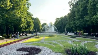 Varşova, Polonya - 03 Eylül 2025: Çeşmeli bir parkın manzarası ve çevrenin tadını çıkaran insanlar, canlı yeşillikleri yakalamak için kamera tavaları