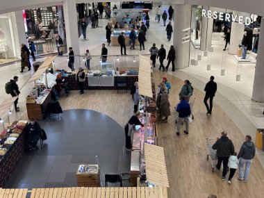 Varşova, Polonya - 20 Kasım 2025: Tatil alışverişçileri ile dolu yoğun alışveriş merkezi bayram hediye tezgahlarına ve dekorasyonlara göz atıyor, Noel ruhunu ve ambiyansı yakalıyor