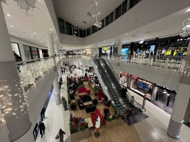 Varşova, Polonya - 20 Kasım 2025: Noel ışıkları ve dekorasyonlarla süslenmiş alışveriş merkezi, Noel ruhunun ve şenlikli atmosferinin keyfini çıkaran müşterilerle dolu