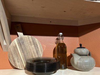 Varşova, Polonya - 20 Kasım 2025: Ahşap tahta, cam yağ şişesi ve seramik çaydanlık mutfak rafında güzel bir şekilde düzenlenmiştir.