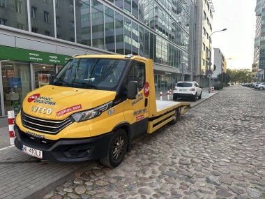 Varşova, Polonya - 28 Ekim 2025: Sarı IVECO çekici kentteki kaldırım taşı caddesinde park halinde, kentsel çevre ve yardım hizmetlerini vurguluyor