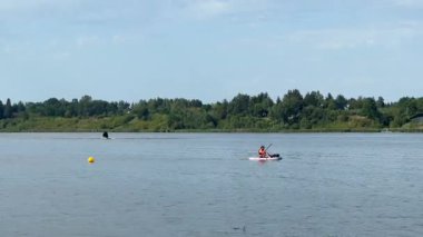 Varşova, Polonya - 28 Ağustos 2025: Kayakçı arka planda su sporları ve doğal güzelliğin heyecanını vurgulayan bir jet ski yarışırken sakin sularda geziniyor