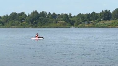 Varşova, Polonya - 28 Ağustos 2025: Turuncu can yeleği giyen kanocu yemyeşil göllerle çevrili sakin gölde geziniyor, kamera yavaş yavaş anı yakalamak için yakınlaşıyor