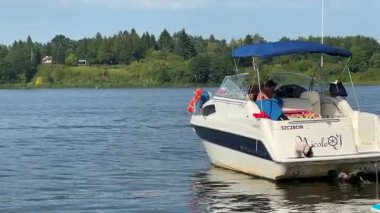 Varşova, Polonya - 28 Ağustos 2025: NicoleJ adlı tekne sakin bir göle demirledi, kamera giderek çevresindeki doğayı ve huzurlu atmosferi göstermek için uzaklaşıyor