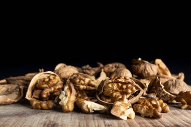 Cevizler ve kabukları ahşap bir kırsal masa üzerinde siyah bir zemin ile