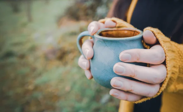 Young woman hands holding a blue mug of tea outdoor — Zdjęcie stockowe
