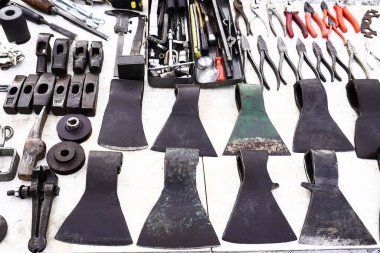 Old rusted flat iron for sale at flea market and more objects. Especially a lot of different old axes                      