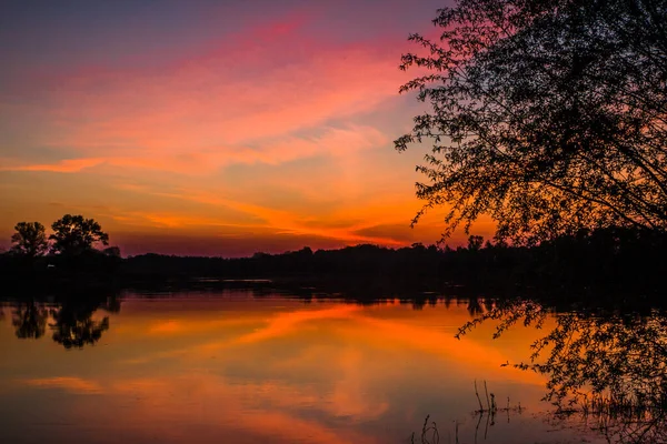 Leuchtend Orangefarbener Sonnenuntergang Über Einem Teich Mit Baumsilhouetten — Stockfoto