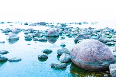 Canlı, renkli ve parlak bir arka plan, manzara. Deniz ya da okyanus kıyısında ya da nehir kıyısında, göl ya da kilosu sakin havalarda su yüzeyiyle kaplı brüt granit kaya ve taş manzarası veya görüntüsü