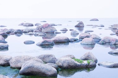 Canlı, renkli ve parlak bir arka plan, manzara. Deniz ya da okyanus kıyısında ya da nehir kıyısında, göl ya da kilosu sakin havalarda su yüzeyiyle kaplı brüt granit kaya ve taş manzarası veya görüntüsü