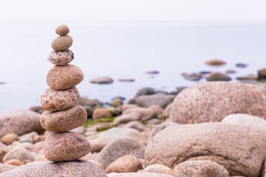 Deniz, okyanus, göl ya da nehir kıyısında yaz ya da sonbahar güneşli günlerinde granit taş ya da kaya piramidi. Canlı, parlak ve renkli deniz manzarası veya manzarası