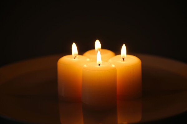 Candles with reflection on a white plate