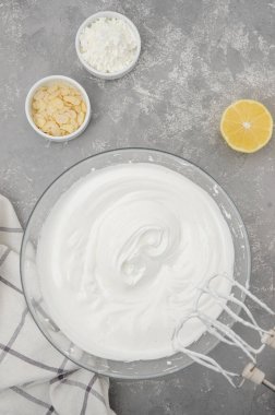 Kremalı Pavlova keki pişiriyorum. Çırpılmış yumurta beyazı ve gri beton arka plandaki kasede şeker. Adım adım tarif et. Dikey, Üst Görünüm