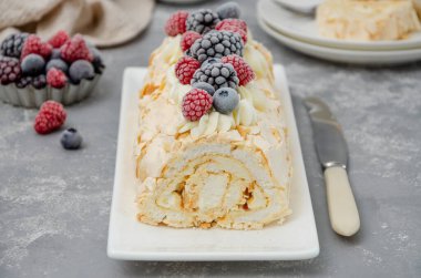 Kremalı, ahududulu, böğürtlenli ve gri arka planda yabanmersinli kremalı Pavlova pastası. Boşluğu kopyala