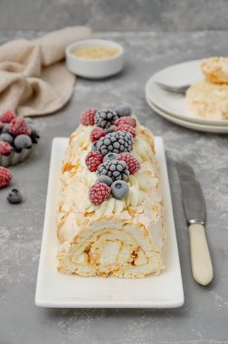 Kremalı, ahududulu, böğürtlenli ve gri arka planda yabanmersinli kremalı Pavlova pastası. Boşluğu kopyala