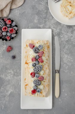 Kremalı, ahududulu, böğürtlenli ve gri arka planda yabanmersinli kremalı Pavlova pastası. Boşluğu kopyala