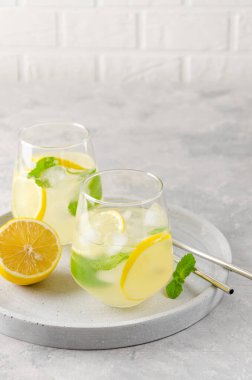 Limonlu, naneli ve buzlu geleneksel limonata gri beton arka planda metal pipetli. Yaz içkisi. Boşluğu kopyala