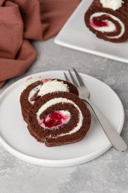 Krem şantili ve vişneli Black Forest çikolatalı kek rulosu gri bir arka planda. Boşluğu kopyala