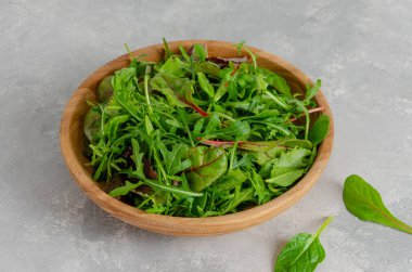 Ahşap bir kasede gri beton arka planda taze salata yaprakları karışımı. Sağlıklı yiyecekler. Boşluğu kopyala