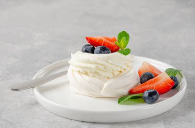 Krem şantili mini Pavlova pastası ve gri beton arka planda bir tabakta taze böğürtlen. Yaz tatlısı. Boşluğu kopyala