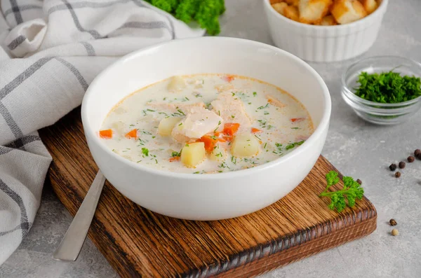 Salmon soup with cream, potatoes, carrots, herb and croutons in a bowl on a gray concrete background. Copy space