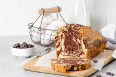 Gri beton arka planda bir tahtada bir somun mermer pastanın üzerinde. Boşluğu kopyala