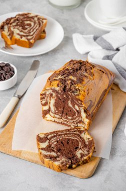 Gri beton arka planda bir tahtada bir somun mermer pastanın üzerinde. Boşluğu kopyala